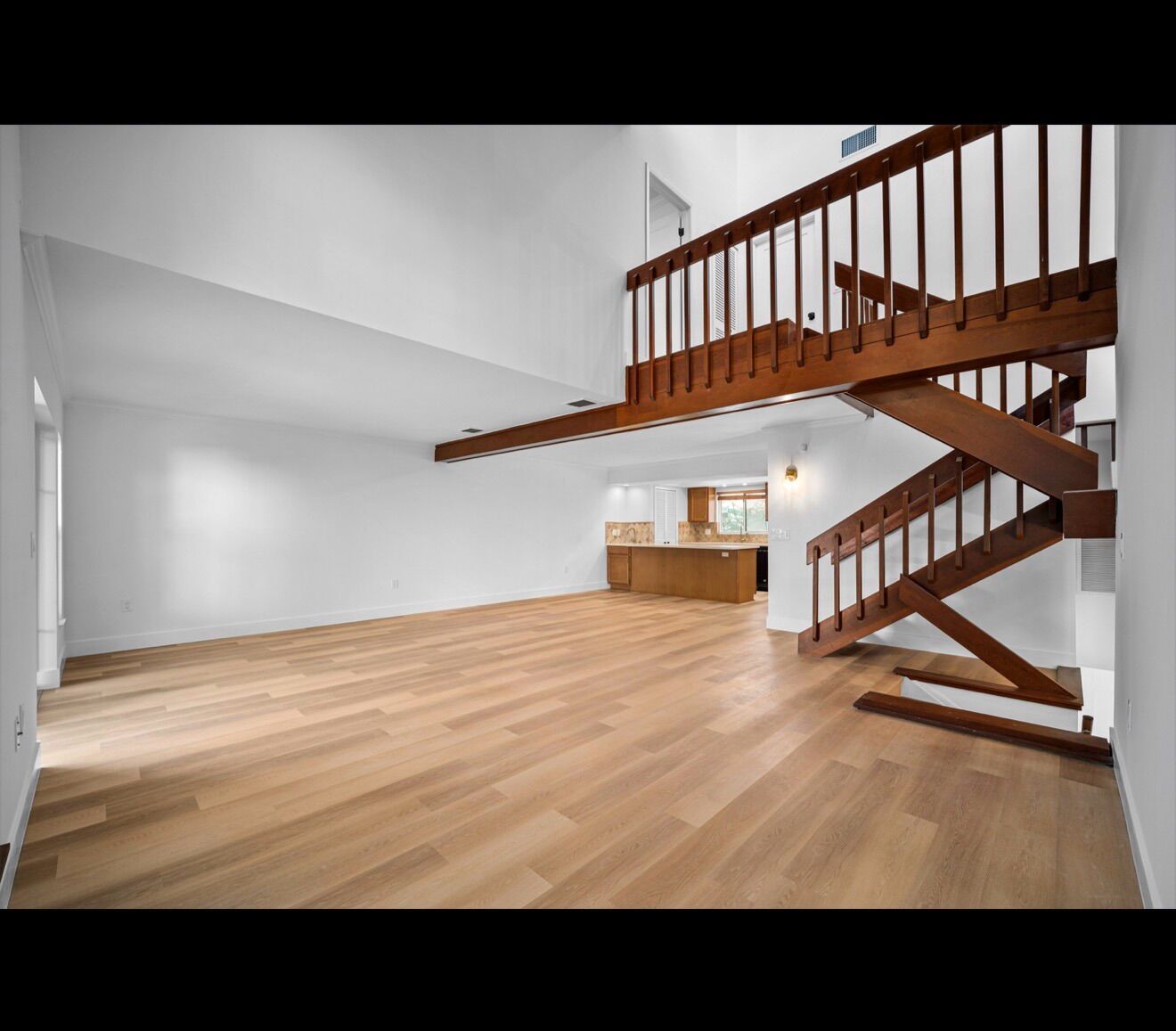 Finished open-concept living area with hardwood floors and open staircase