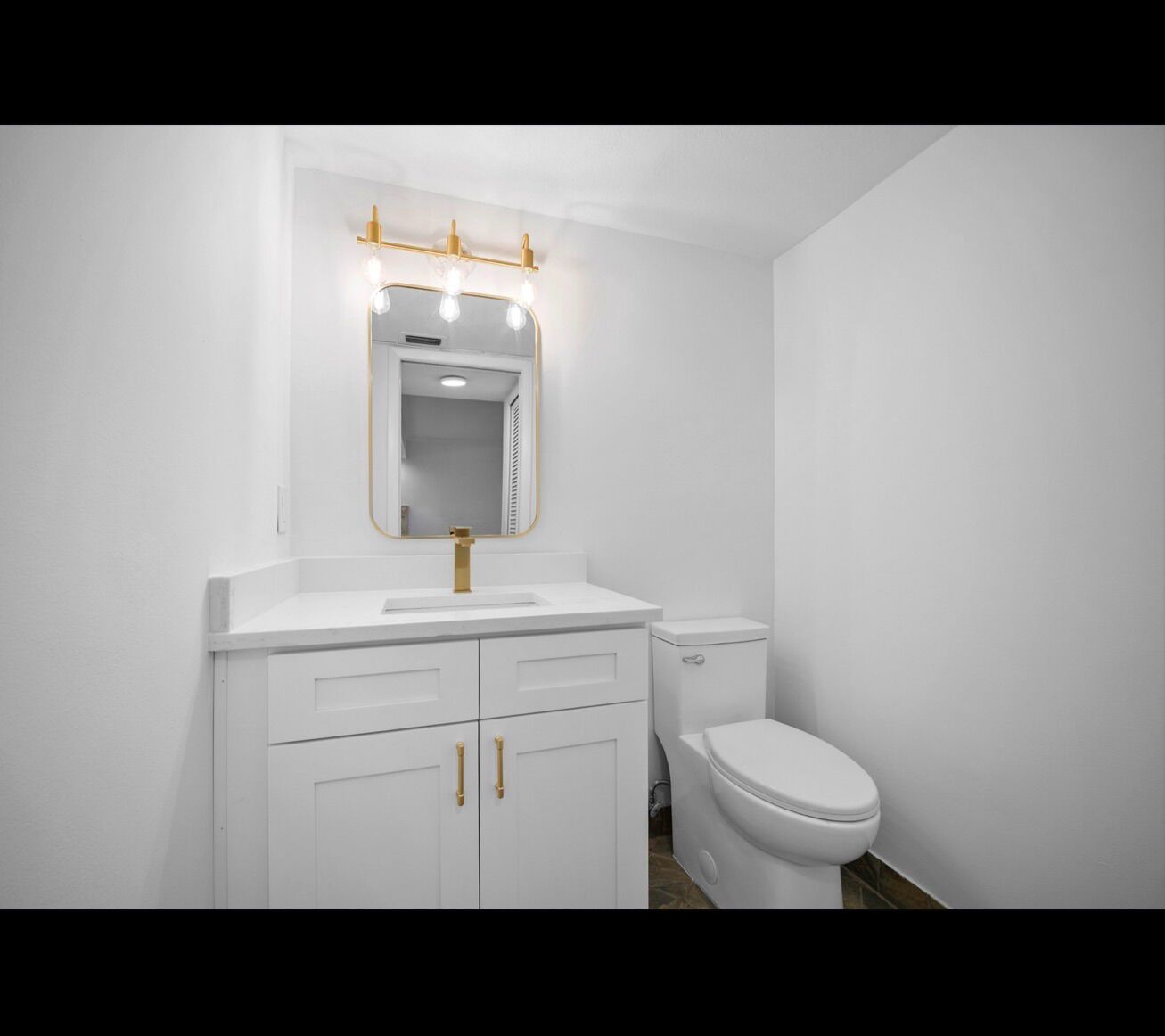 Finished bathroom with white vanity and gold fixtures