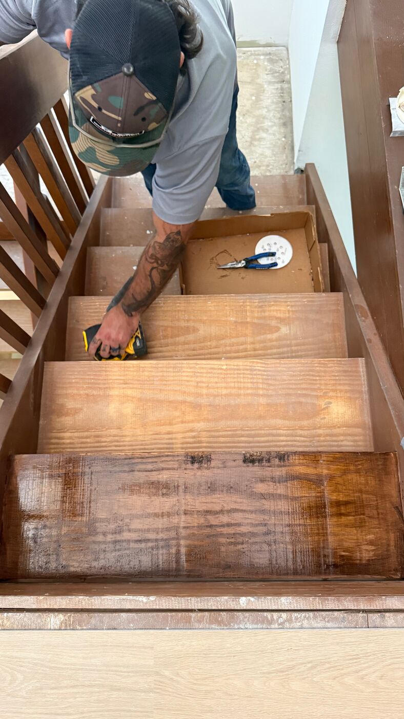 Worker sanding and staining stair treads